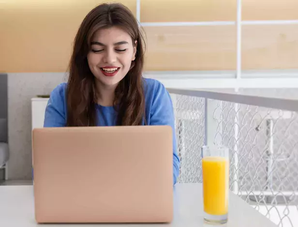 attractive-young-woman-in-blue-sweater-works-at-laptop-in-cafe-compressed